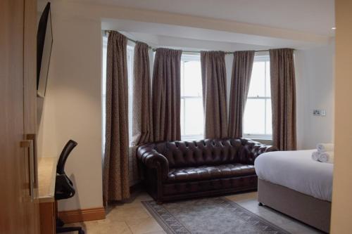 a bedroom with a leather couch in front of a window at Osborne Aparthotel in Eastbourne