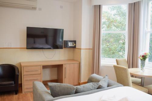 a living room with a couch and a tv at Osborne Aparthotel in Eastbourne