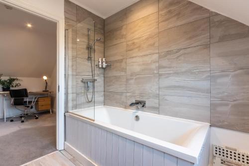 a bath tub in a bathroom with a shower at Cotswold holiday let with hot tub - The Old Garage in Chipping Norton