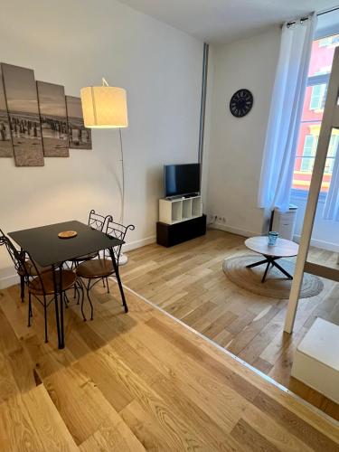 un salon avec une table, des chaises et une télévision dans l'établissement Place Massena, à Nice