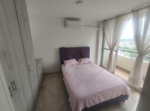 Un dormitorio pequeño con una cama y una ventana. en Reserva del Peñon, en Girardot