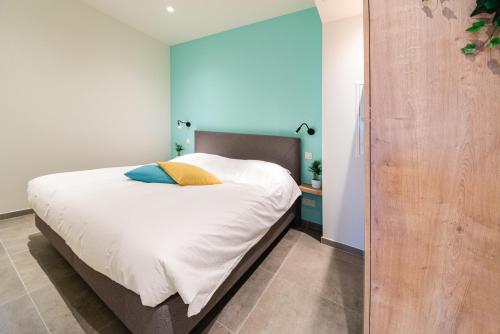 a bedroom with a bed with white sheets and blue walls at SYBA Gastenverblijf in Evergem