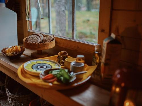 a table with a plate of food and a window at Cozy a-frame in the woods in Enontekiö