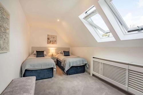 a attic bedroom with two beds and a window at Cotswold holiday let with hot tub - The Old Garage in Chipping Norton