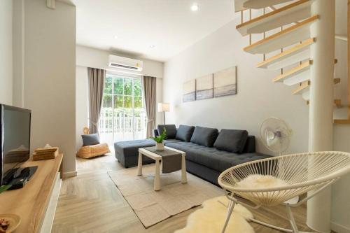a living room with a blue couch and a tv at Naka Cozy House in Phuket City in Ban Rangeng