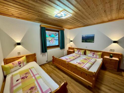 a bedroom with two beds and a wooden ceiling at wolf.tirol in Ladis