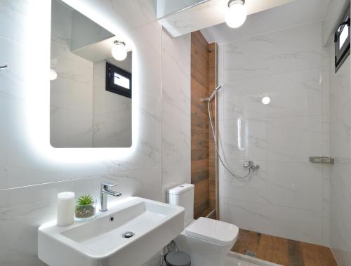 Baño blanco con lavabo y espejo en Villa Chrisanthi, en Leptokarya