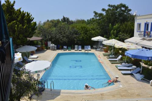 two people swimming in a swimming pool with umbrellas at Paradise Garden Apartments in Gumusluk