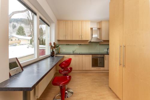 a kitchen with a counter and a red stool at Ski-In/Ski-Out Appartements Augasse by Schladming-Appartements in Schladming
