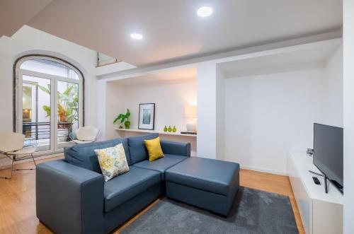 a living room with a blue couch and a tv at Ponta Delgada Flats - HOST & CHILL in Ponta Delgada
