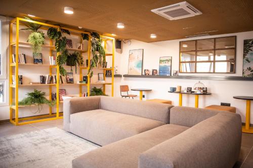a living room with a couch and shelves with plants at JOST Hôtel Le Havre Centre Gare in Le Havre