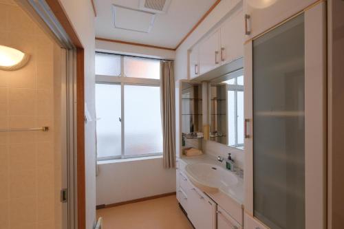 uma casa de banho com um lavatório e uma janela em Guest House Umikaji em Naha