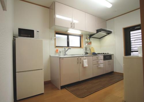 cocina con armarios blancos, fregadero y nevera en たび宿SeKKoku en Takagi