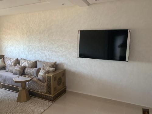 salon z kanapą i telewizorem z płaskim ekranem w obiekcie Apparemment avec piscine w mieście Kenitra