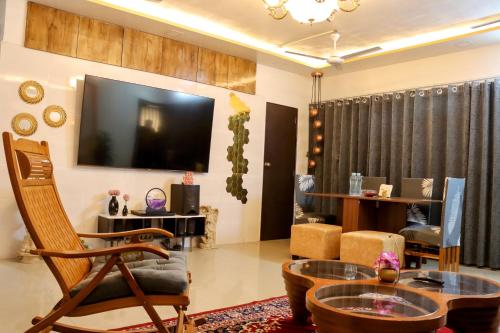een woonkamer met een televisie en een tafel en stoelen bij Zoey's Hill View - 120" 4K Projection Cinema, Jacuzzi, Party Up in Navi Mumbai