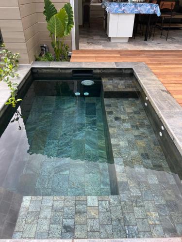 a swimming pool in a yard with a patio at La Villa Paille en Queue in Saint-Gilles les Bains