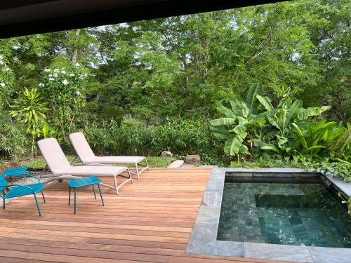 a wooden deck with chairs and a swimming pool at La Villa Paille en Queue in Saint-Gilles les Bains