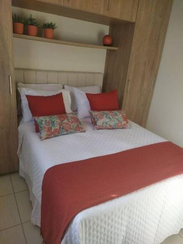 a bed with red and white sheets and pillows at Apartamento Aconchegante in Brasília