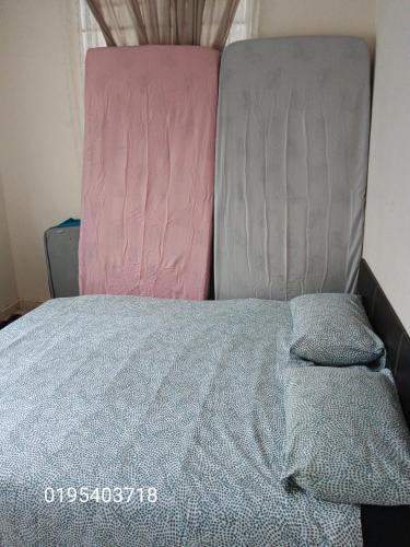 a bed with a pink and grey comforter at Homestay Othman Perlis-14pax-AC-Wifi-Kangar-BBQ in Kangar
