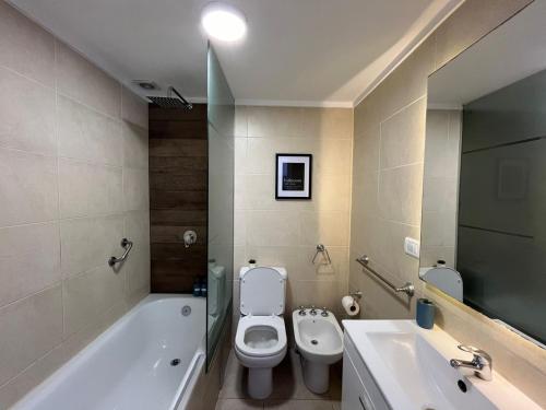 a bathroom with a toilet and a tub and a sink at La Perla I in Mar del Plata