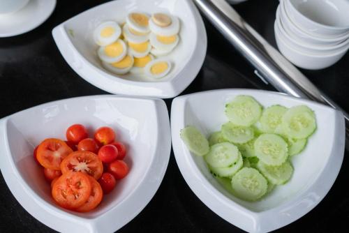 three plates of food with tomatoes and eggs on a table at LuangPrabang Center Hotel in Luang Prabang