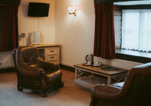 a living room with a chair and a table at The Heathfield Inn in Honiton