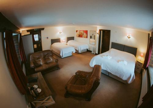 ホニトンにあるThe Heathfield Innのベッド2台と椅子が備わる広いホテルルームです。