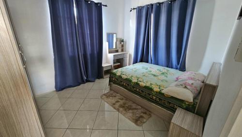 a small bedroom with blue curtains and a small bed at Villa MCaesa in Pointe aux Sable