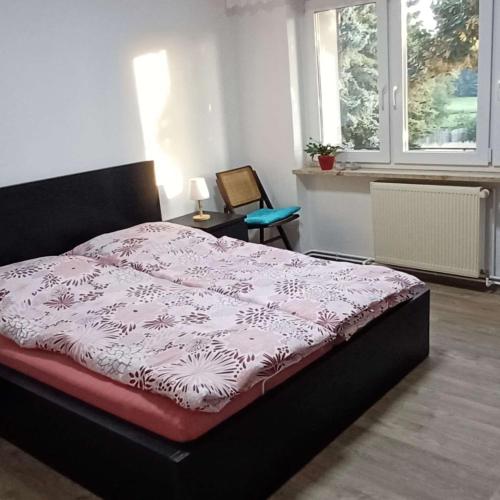 ein Schlafzimmer mit einem Bett mit einer rosa-weißen Bettdecke in der Unterkunft Berlin - Potsdam - Fläming in Trebbin