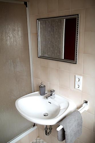 ein Badezimmer mit einem weißen Waschbecken und einem Spiegel in der Unterkunft Ferienwohnung Ruttner in Rastatt