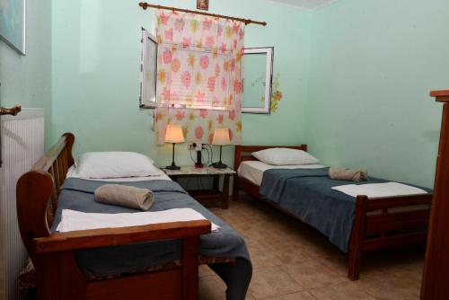 a bedroom with two beds and a window with a curtain at Xenios Dias in Megáli Vrísi