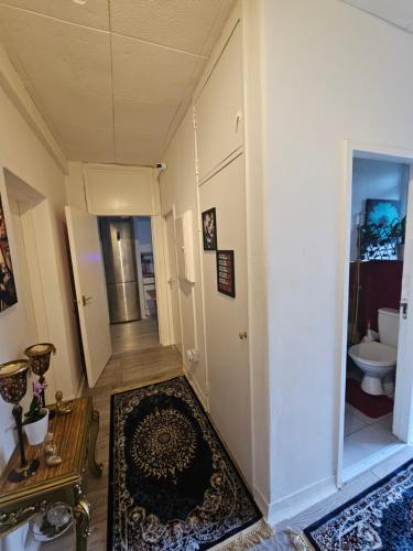 a hallway with a room with a toilet and a rug at Cheshunt House in London