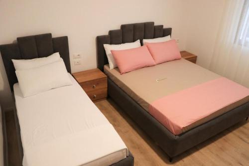 een slaapkamer met 2 bedden met roze en witte kussens bij Albora Guest House in Fier
