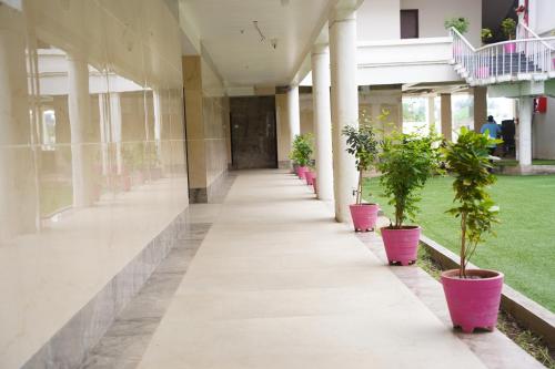 ein leerer Korridor eines Gebäudes mit Topfpflanzen in der Unterkunft Hotel Millennium Plaza in Jamnagar