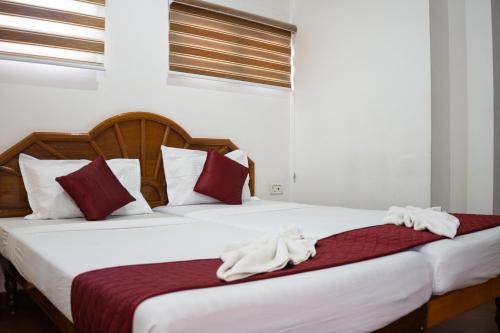 a bedroom with two beds with red and white pillows at Marine Palace Beach Hotel in Kovalam