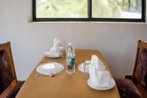 a table with plates and a bottle of water on it at Marine Palace Beach Hotel in Kovalam