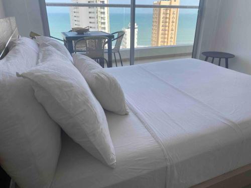 ein weißes Bett mit Kissen und Blick auf einen Balkon in der Unterkunft !Nuevo, Lujoso y vista al mar ! in Cartagena de Indias