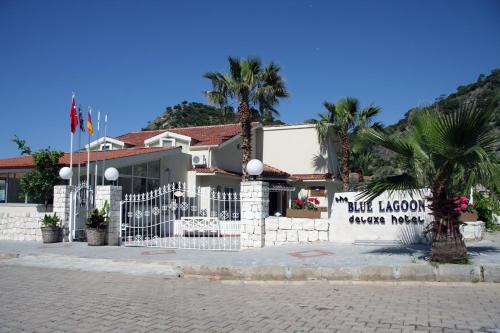 a building with a white fence and palm trees at The Blue Lagoon Deluxe Hotel in Oludeniz
