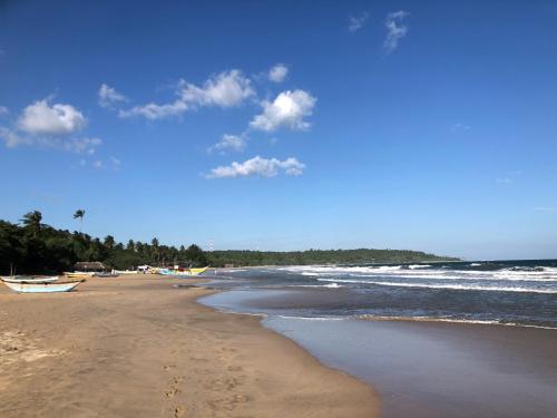 a beach with boats on the sand and the ocean at Simplex Sea Place in Tangalle