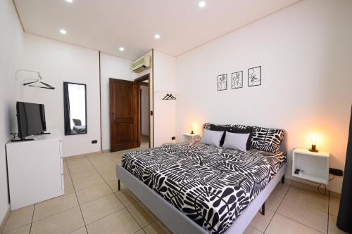 1 dormitorio con 1 cama en blanco y negro y TV en Alleria, en Comiso