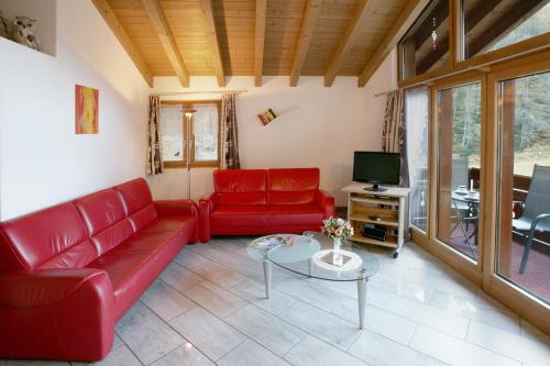 a living room with a red couch and a tv at Appartement Flora in Saas-Almagell