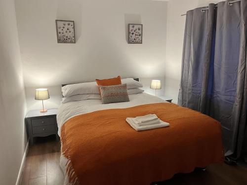 Impeccable 3-Bed House in Nottingham في نوتينغهام: غرفة نوم مع سرير برتقالي كبير مع مصباحين
