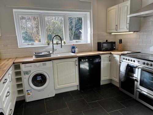 a kitchen with white cabinets and a sink and a dishwasher at Impeccable 3-Bed House in Nottingham in Nottingham