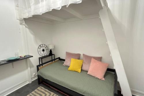 a bed with pink and yellow pillows in a room at Cozy studio in Paris 15eme in Paris