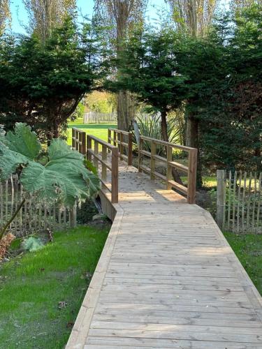 un pont en bois dans un parc avec une clôture dans l'établissement Domaine de l'O, à Gatteville-le-Phare