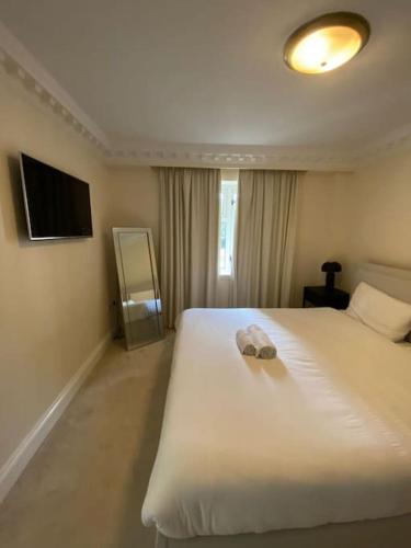 a bedroom with a white bed with a towel on it at Newly refurbished apartment, near station & river in London