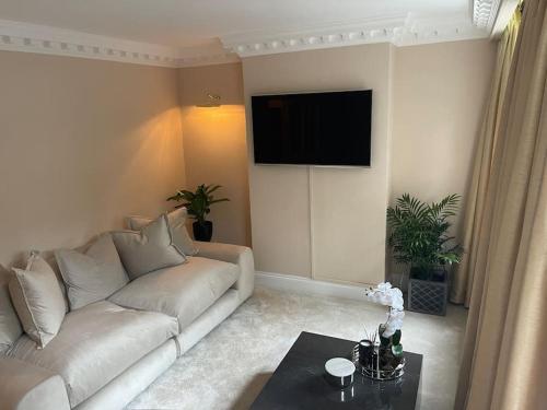 a living room with a white couch and a flat screen tv at Newly refurbished apartment, near station & river in London