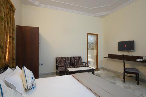 a bedroom with a bed and a chair and a television at Sudarshan Homestay in Jodhpur