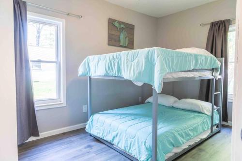 ein Schlafzimmer mit einem Etagenbett mit blauer Bettwäsche in der Unterkunft Modern Downtown Gem - Close to Beach - Yard - Pkg! in Port Austin