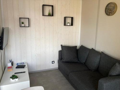 un salon avec un canapé et une horloge au mur dans l'établissement COTTAGE 4/5 pers, à Jullouville